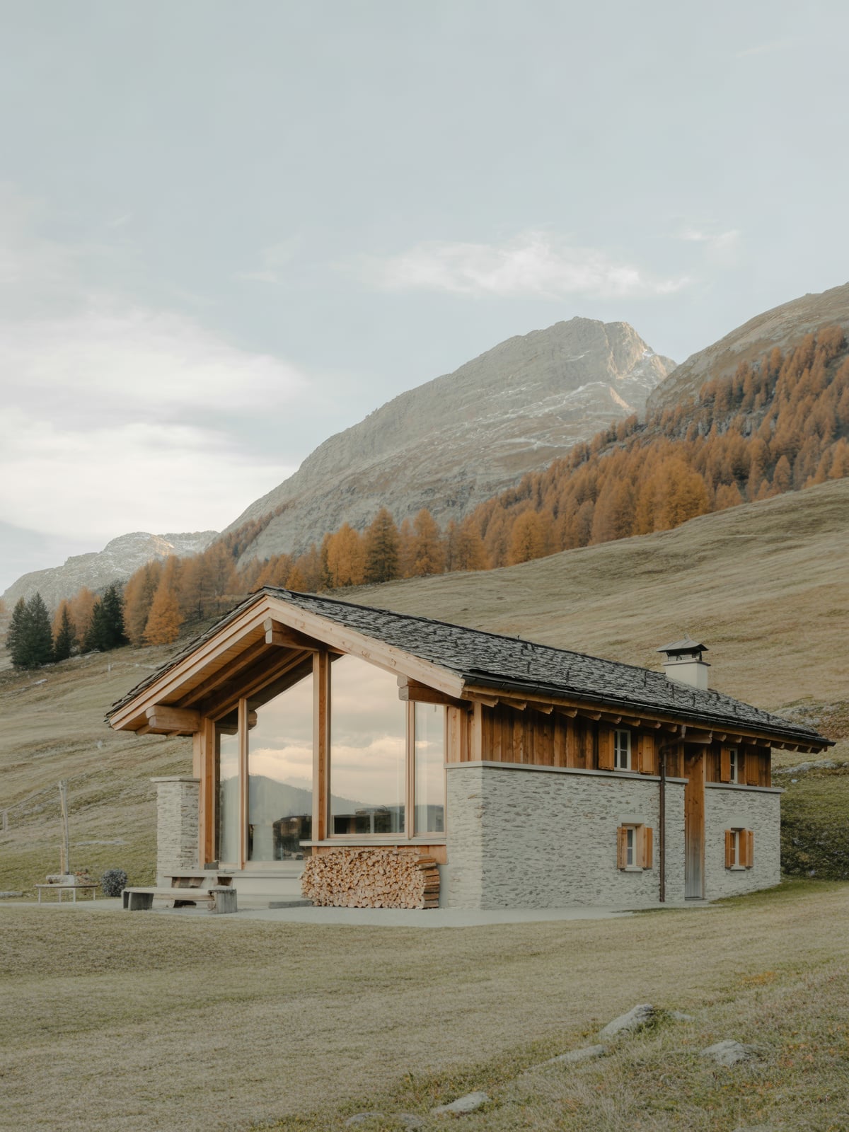 Zeitgenössisches Chalet aus Lärchenholz und Naturstein auf einer herbstlichen Alpwiese
